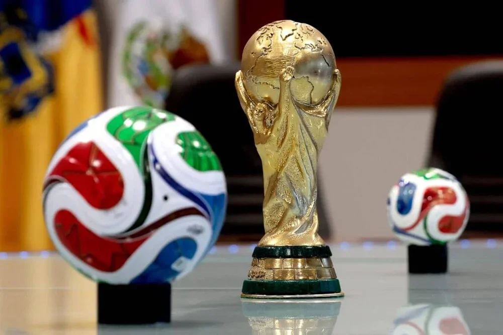 An image of the World Cup trophy and two World Cup footballs
