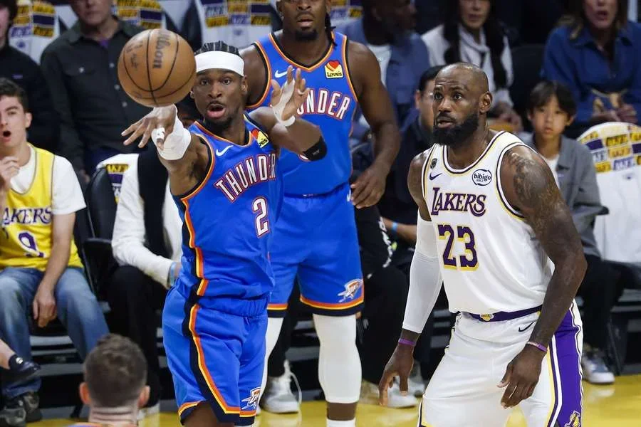 Shai Gilgeous-Alexander del Thunder pasa el balón ante la defensa de LeBron James